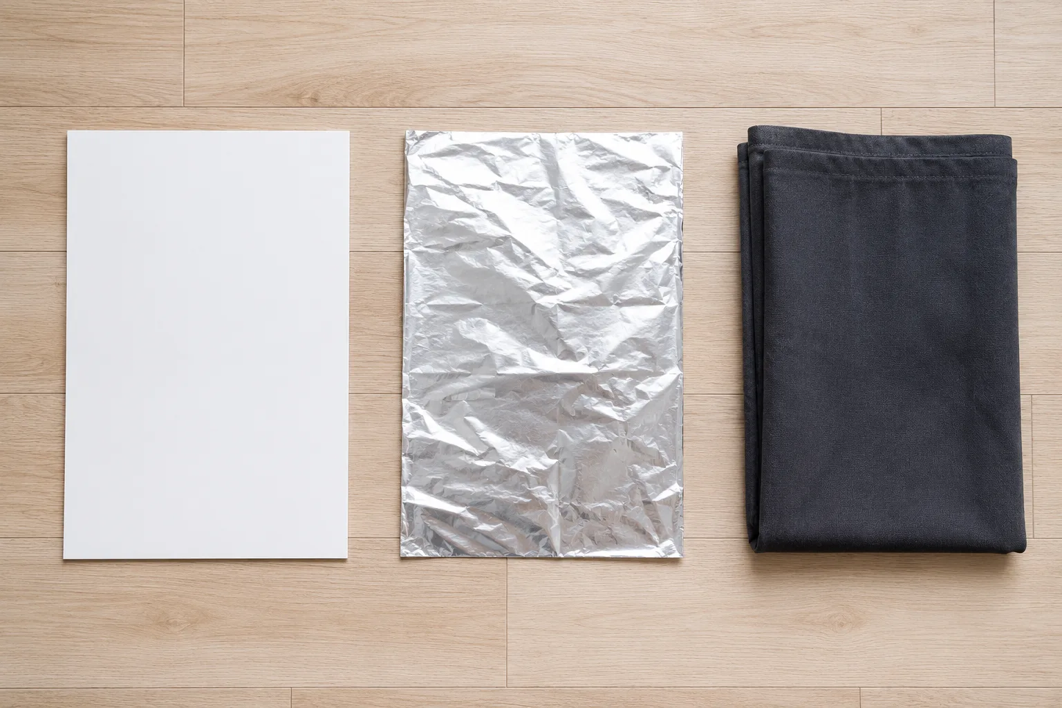 White foam board, creased mylar sheet and folded blackout curtain laid side by side to block grow light leak